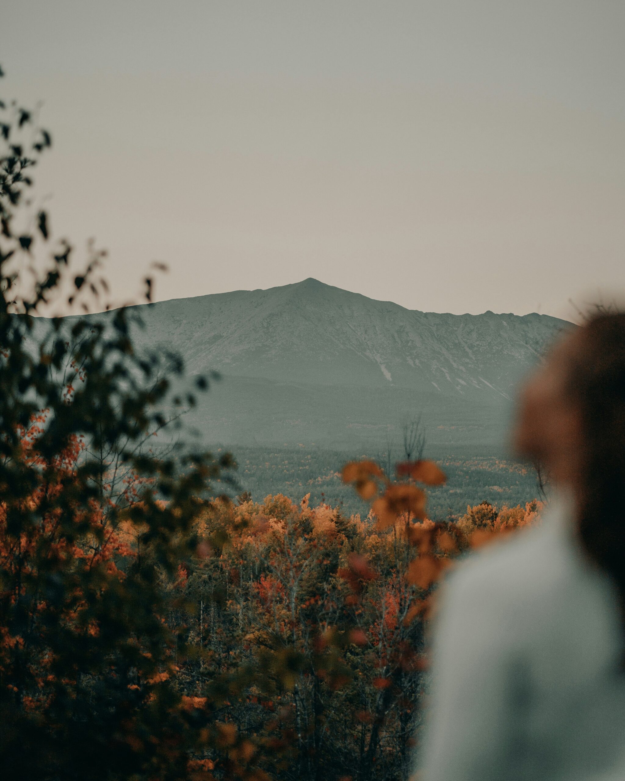 A person standing in front of Mount Katahdin in autumn.